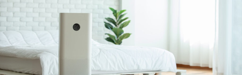 Air purifier in cozy white bedroom for filter